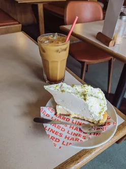 Key lime pie with sweet tart lime layer and buttery base, paired with iced oat cinnamon honey latte at Hard Lines, Cowbridge Road East.