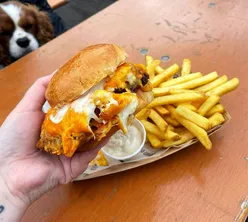 Parmos and pints on a sunny day at HWKR Land NCL, with a playful dog in the background. Enjoy food and drinks from Parmorama.