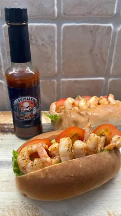 Spicy Shrimp Poโ Boys with Cajun prawns, crispy lettuce, tomato, and zesty Louisiana hot sauce mayo on a soft bun.