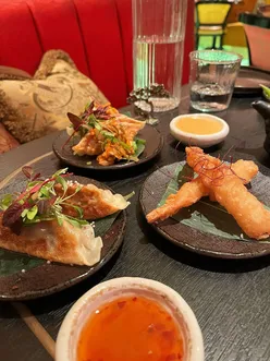 Opulent Ivy Asia setting with prawn har gow dumplings, pork kimchi gyoza, and ebi prawn tempura with chili lime dressing.