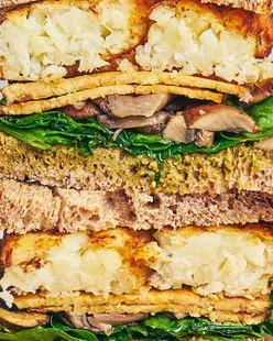 Toasted sourdough sandwich with pesto, garlicky mushrooms, spinach, crispy Tiba smoky tempeh, and hash browns.