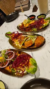 Delicious dishes at Amrut Leicester, including Malai Chicken, Mewari Seek Kebab, and Paneer Makhani in a vibrant setting.