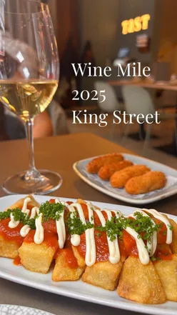 Wine lovers enjoying free glasses of wine during Wine Mile at King Street, Manchester, with various participating venues.