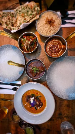 Enjoying a delicious spread of Indian cuisine at Black Cumin in Bristol, featuring lamb chops, butter chicken, and naan.