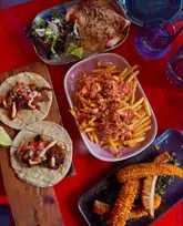 Delicious Mexican feast at Cabo in Edinburgh, featuring corn ribs, loaded fries, enchiladas, and steak tacos.