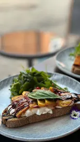 Brunch at Ovation Bar featuring small plates like smoothie bowls, avocado toast, and iced coffees in a cozy setting.