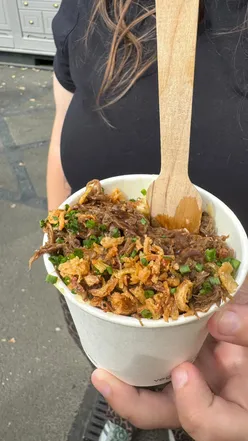 Exciting food battle scene showcasing gourmet burgers, wings, and mac and cheese at a vibrant Newcastle event.