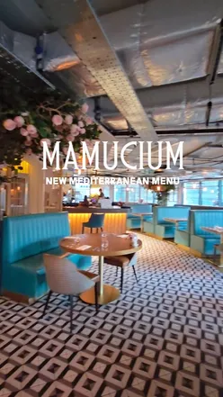 Diners enjoying Mediterranean dishes like hummus, grilled sea bass, and desserts at Mamucium Restaurant in Manchester.