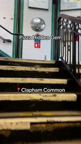 Food reviewer enjoying pizza at a Clapham restaurant, sharing a fun anecdote about the area.