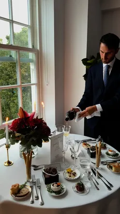 Couple celebrating anniversary at home with elegant dinner setup, featuring pasta, truffle risotto, and cocktails.