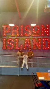 Friends teaming up for a fun challenge at Prison Island Experience in London, featuring themed cells and teamwork.
