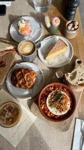 Artisan dishes and coffee at Faun Bakery & Café in Malvern, Worcestershire, featuring sausage sandwich and sweet treats.