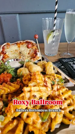 Group enjoying bottomless brunch and games at Roxy Ballroom, Liverpool, with drinks and delicious American-style food.