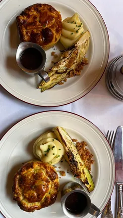 Guests enjoying hearty pies and drinks at the historic Newman Arms pub in Fitzrovia, London. Cozy atmosphere, delicious food.