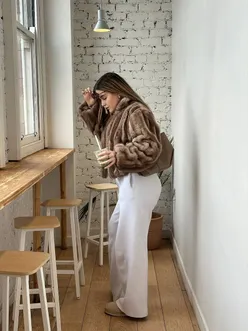Person enjoying matcha in autumn outfit, featuring a fur coat and UGGs, at a trendy Manchester café.