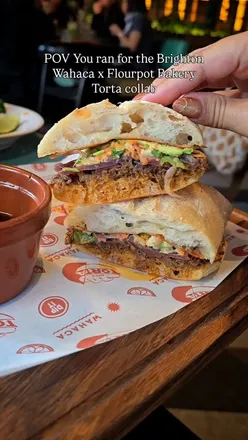 Delicious birria sandwich with slow-cooked beef, avocado, and pickled veggies, served with dipping sauce at Wahaca.