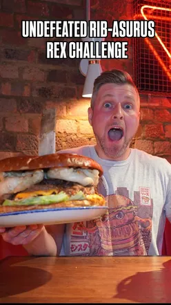 Participant tackling the UNDEFEATED RIB-ASURUS REX Challenge at Camden Diner with massive burger and ribs.