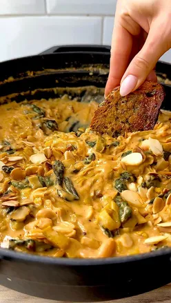 Mustardy Cavolo Nero Beans recipe with leeks, garlic, and cannellini beans, garnished with toasted almonds.