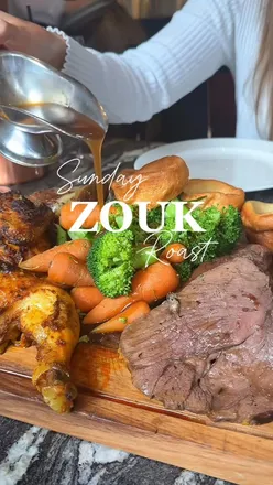 Sunday roast platter at Zouk Manchester with roast poussin, lamb, beef, crispy roasties, and delicious cocktails.