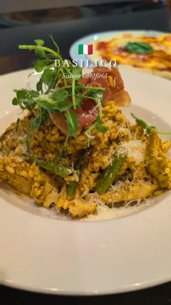 Diners enjoying garlic bread, scallops, Margherita pizza, and chocolate fudge cake at Basilico Italian restaurant.