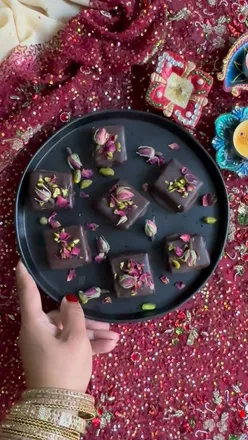 Chocolate-coated barfi adorned with rose petals and pistachios, perfect for Diwali celebrations at Dr Chintal's Kitchen.