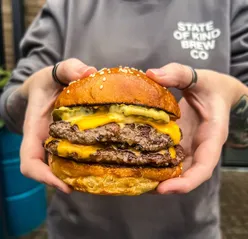 Craft beer lovers enjoying burgers and small plates at The Brewery Project by State of Kind in Wigan.