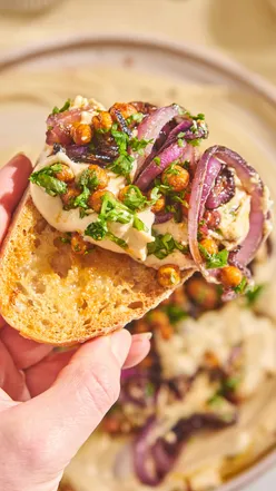 Enjoying creamy roasted garlic hummus with caramelised onions and spiced chickpeas at home, perfect for autumn vibes.