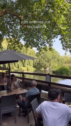 Riverside view of The Saxon Mill in Warwick, showcasing its cosy pub interior and scenic terrace.