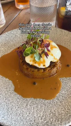 Guests enjoying lunch at The Jigger Inn with views of the Old Course in St Andrews, featuring haggis crumpet and Scottish pub fare.