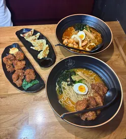 Diners enjoying a variety of dishes at Maki & Ramen in Leeds City Centre, featuring gyoza, ramen, and sushi rolls.