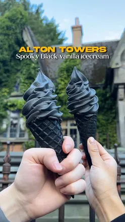 Spooky black vanilla ice cream enjoyed at Alton Towers during Halloween festivities, with festive decorations in the background.