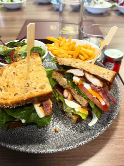 Delicious club sandwich stacked high with fresh ingredients, served in a vibrant restaurant setting.