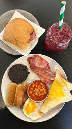 Scottish Breakfast and coffee at The Coffee Connection in Edinburgh, featuring a bacon roll, smoothie, and flat white.