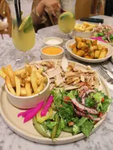Chicken Shawarma platter with salad, fries, and Passionfruit Fizz mocktails at Bakchich, a Lebanese-Moroccan restaurant.
