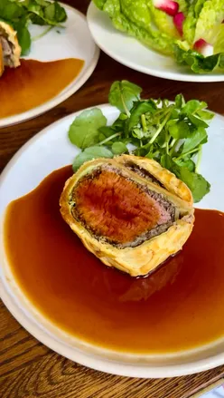 Diners enjoying beef wellington and chorizo yoghurt at Sussex Resto in Soho, showcasing seasonal British cuisine.