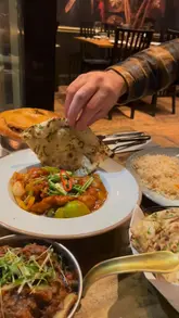 Diners enjoying a vibrant curry meal at Black Cumin in Cotham Hill, Bristol, featuring prawns and lamb chops.