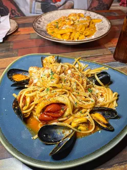 Del Villagio in Birmingham featuring a delicious Italian meal with arancini, linguine, tiramisu, and vibrant cocktails.