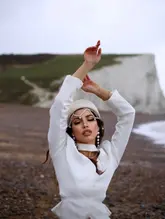 A high-quality portrait of a woman posing in front of the Seven Sisters cliffs, capturing a travel-focused lifestyle aesthetic.