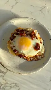 A short, top-down video demonstrating a simple egg recipe on a crumpet. The video focuses on the cooking process and the final result, using quick cuts to maintain interest.
