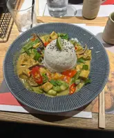 A top-down, well-lit photograph of a tofu raisukaree curry served at Wagamama. The image captures the dish clearly, though the surrounding table setting, including a water glass and placemat, creates a cluttered background that detracts from the food itself.