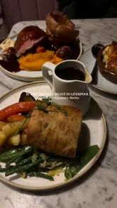 A short, edited montage showcasing a Sunday roast experience at Little Leaf in Liverpool, focusing on a vegan mushroom Wellington, gravy pouring, and the restaurant's interior.