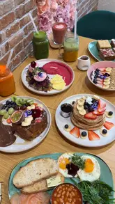A montage showcasing the food, drinks, and interior aesthetic of 50Nine, a brunch cafe with a floral-themed decor. The video features close-ups of various dishes including pancakes, a mixed grill, and coffee, highlighting the presentation and the venue's unique atmosphere.