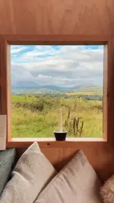 A montage of a couple's stay in a scenic cabin, featuring shots of the interior, the surrounding nature, a hot tub, a fire pit, and a cocktail.