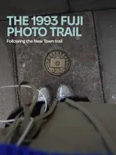 A first-person perspective shot looking down at a brass 'Fuji Photo Trail' plaque embedded in a grey pavement. The image is moody and atmospheric, capturing a local Edinburgh activity.