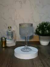 A product shot featuring a glass of Pentire non-alcoholic spirit with tonic, displayed on white foam plinths against a marble-effect background with a small potted plant.