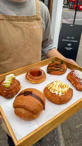 A fast-paced, engaging vlog-style video showcasing a London bakery. The creator highlights the variety of pastries, the preparation process, and their personal enjoyment of the food, effectively communicating the bakery's appeal.