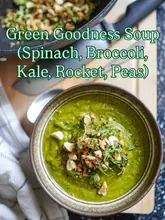 A high-quality, overhead shot of a vibrant green soup topped with nuts and herbs, presented in a rustic bowl on a wooden surface. The image is well-lit and styled, effectively showcasing the texture and freshness of the dish.