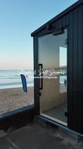 A short, aesthetic video tour of the new sauna cabins located on Tynemouth Longsands beach. The footage highlights the exterior of the cabins, the interior wood-panelled sauna room with a wood-burning stove, and the scenic view of the beach and sea.