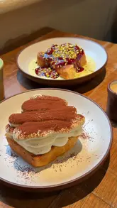 A short, aesthetic reel showcasing various vegan brunch dishes at Mallow, including a full English breakfast, a market meze platter, and two types of French toast. The video uses slow-motion close-ups to highlight the textures and presentation of the food.