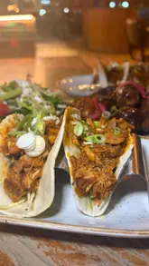 Couple enjoying bottomless tapas at La Iguanas in Bolton, featuring tacos, chicken wings, and a vibrant atmosphere.